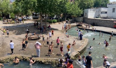 Diyarbakır’da çocuklar ailelerinin nezaretinde süs havuzunda serinliyor
